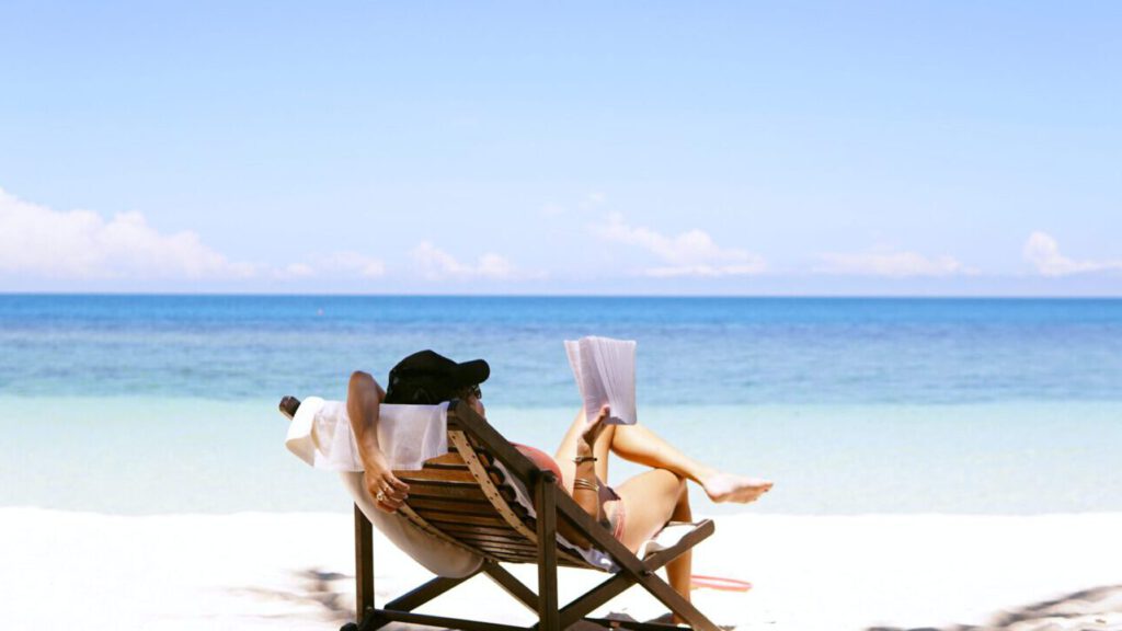 woman sits on brown wooden beach chair